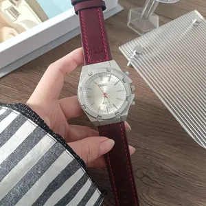 Primo piano di un orologio al quarzo argento con cinturino in pelle bordeaux su legno