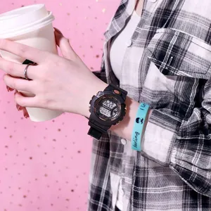 Primer plano de un reloj deportivo digital negro usado en la muñeca con fondo de camisa a cuadros