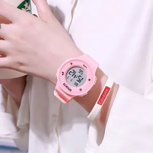 Detailed view of a pink digital sports watch and white silicone bracelet worn on wrist