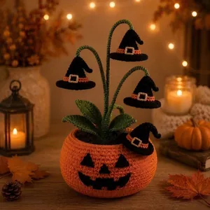Detailansicht eines handgehäkelten Halloween-Kürbistopfes mit schwarzen Hexenhüten als Deko