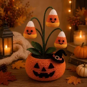 Makroaufnahme eines handgehäkelten Halloween Kürbis-Topfes mit Zuckermais-Glockenblumen