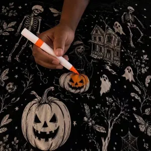Detail view of a hand using an orange marker to color a Halloween pumpkin blanket