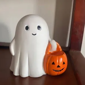 Gros plan d'une figurine de fantôme en résine tenant un seau de citrouille d'Halloween.