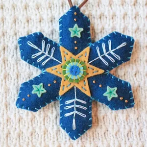 Detailed view of handmade blue felt Christmas snowflake ornament with embroidery