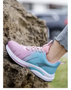 Vista lateral detallada de zapato de seguridad rosa y azul degradado para mujer sobre rocas