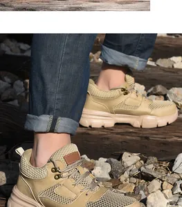 Primer plano de zapatos de seguridad caqui con punta de acero en un entorno ferroviario exterior.