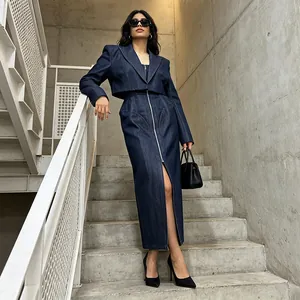 Full body view of an elegant denim two-piece skirt set shown in an industrial setting.