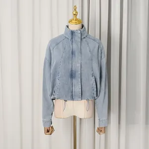 Detail view of a loose light blue denim jacket with stand collar and drawstring hem.