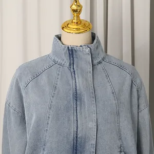 Detail view of light blue denim jacket showing stand collar and raglan sleeve design