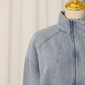 Close-up detail of women's light blue denim jacket featuring stand collar and raglan sleeves