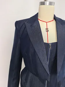 Close-up detail of a dark blue denim blazer featuring a front zipper and structured lapels