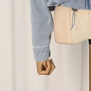 Detail view of a light blue denim jacket sleeve on a stylish wooden mannequin hand.