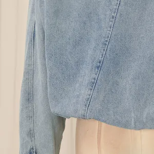 Close-up detail of light blue denim jacket showing fabric texture and stitching