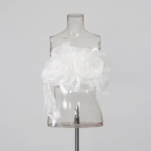 Close-up of white tube top with oversized fabric flower patchwork and ruffle details.