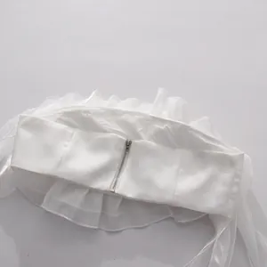 Back view detail of white ruffled strapless top featuring a metallic zipper closure