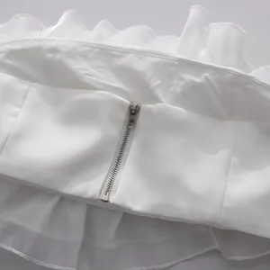 Close-up shot showing high-quality silver metal zipper on white ruffled strapless top detail