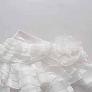Detailed macro view of the layered ruffles and floral accent on a white mini skirt