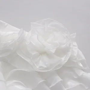 Close-up of white fabric flower and ruffled detailing on women's summer set