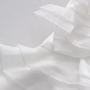 Close-up macro detail of layered white ruffles and fine stitching on this summer outfit