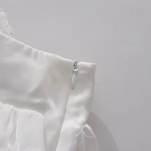 Detail view of high-quality invisible zipper on the side of a white ruffle skirt