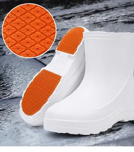 Detailansicht der rutschfesten orangefarbenen Sohle der weißen wasserfesten EVA-Gummistiefel.