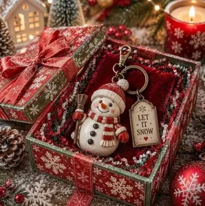Detail of a snowman keychain with 'LET IT SNOW' tag in a festive Christmas gift box