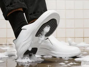 Detalle de la suela antideslizante de zapatos de trabajo blancos en suelo mojado.