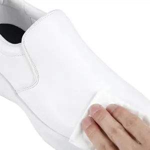 Primer plano limpiando un zapato de trabajo blanco antideslizante, material fácil de limpiar.