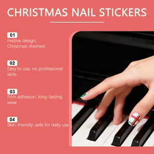 Detailansicht von Weihnachts-Gel-Nagelstickern auf Fingern über Klaviertasten