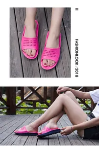 Lifestyle view of comfortable pink and blue non-slip slippers on a wooden deck background.