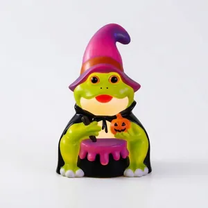 Detalle de una figura de rana de Halloween verde con sombrero de bruja y una pequeña calabaza
