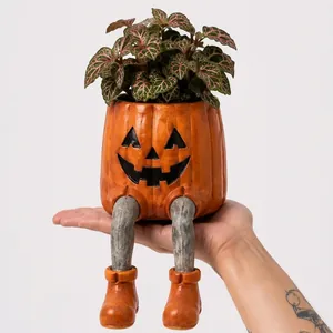 Λεπτομέρεια γλάστρας κολοκύθας Halloween με κρεμαστά πόδια και σκαλιστό πρόσωπο