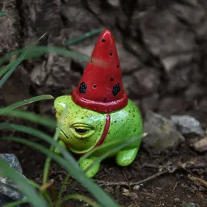 Vista detallada de una figura de rana en miniatura con un gorro rojo puntiagudo