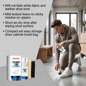 Detailed view of a man using foam cleaner and brush on white leather sneaker shoes