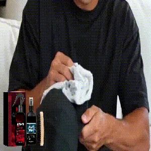 Detail of hat cleaning kit being used to wipe stains off a black fabric baseball cap.