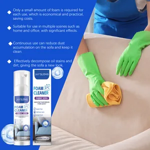 Détail de l'application du nettoyant mousse sur un canapé en tissu avec un chiffon.