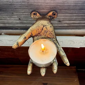 Detailed view of vintage gold hand wall hook holding a small lit candle for atmospheric decor