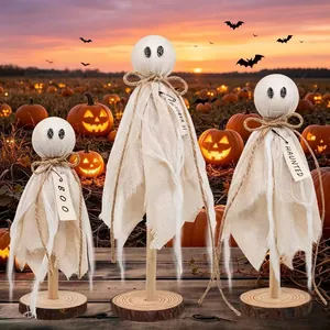 Détail de fantômes en tissu faits main avec étiquettes 'Boo' dans un champ de citrouilles
