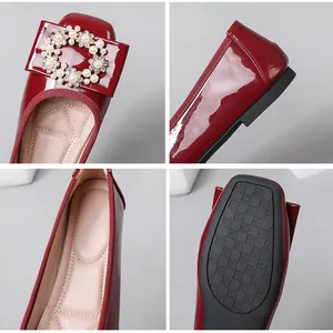 Detailed view of red patent leather ballet flats with elegant pearl and crystal buckle