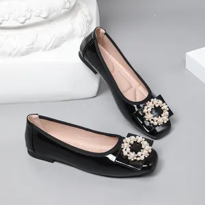 Close-up of black patent leather ballet flats featuring elegant pearl and crystal buckle