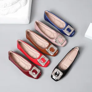 Detail view of various colored patent leather flats with signature rhinestone buckles.