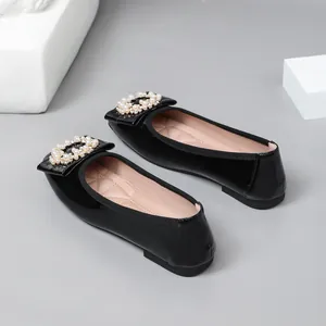 Detailed view of elegant black patent leather ballet flats featuring pearl buckles