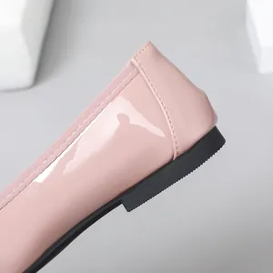 Close-up of pink patent leather flat shoe heel with glossy finish and black sole.