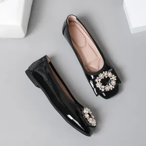 Detail shot of black patent leather ballet flats featuring elegant pearl and rhinestone buckle