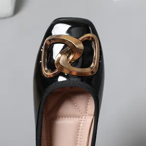 Detailed macro view of black patent leather ballet flats featuring a stylish gold buckle accent