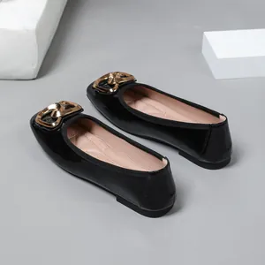 Detailed close-up of women's black patent leather ballet flats featuring gold buckles.