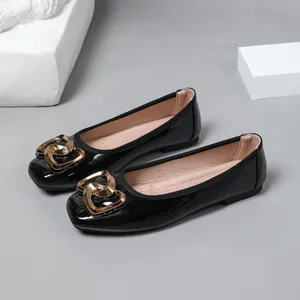 Detail showing black patent leather ballet flats with gold heart buckle ornamentation.