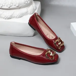 Close-up detail of wine red patent leather ballet flats with decorative gold buckle