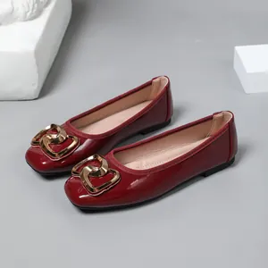 Close-up detail of wine red patent leather ballet flats with elegant gold heart buckle
