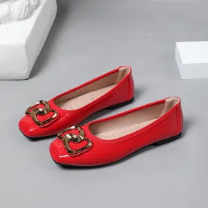 Detailed macro view of vibrant red patent leather ballet flats with elegant gold heart buckle